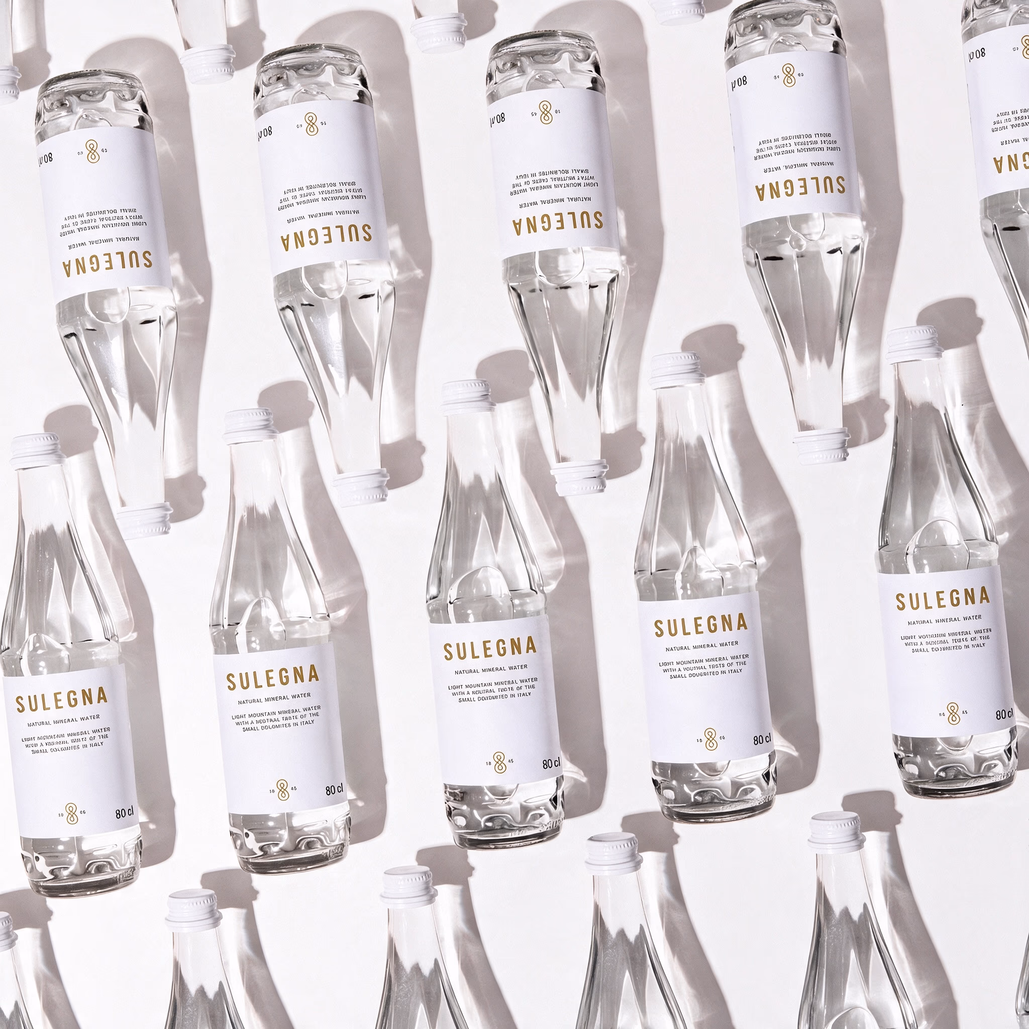 SULEGNA Natural bottles, 80 cl and 44 cl, standing together on a warm neutral background